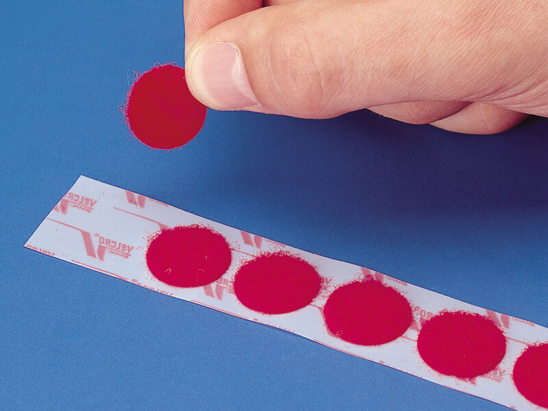 3m dual lock cercles rouges l'illustration montre des petits pads dual lock rouges découpés, dont l'un a été retiré du support pour la présentation. le fond est bleu