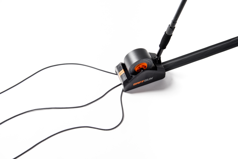 Gaffgun verlegt Kabel im Stehen Schwarzes Gerät, dass mehrere schwarze Kabel am Boden anklebt auf weissem Hintergrund. Auf dem Gerät befindet sich das Logo Gaffgun. Im IBZ Industrie AG Onlineshop erhältlich.