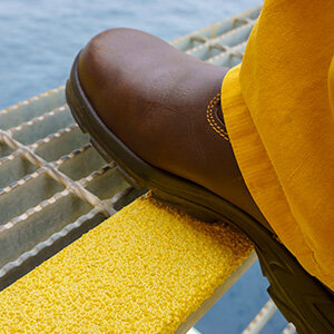Brauner Stiefel tritt auf Treppe mit gelben Antirutsch Belag .
